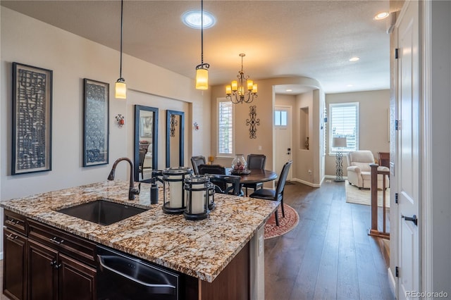 kitchen with dark wood-style floors, decorative light fixtures, open floor plan, a sink, and a textured ceiling