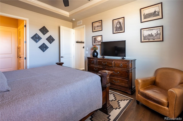 bedroom with crown molding, a raised ceiling, visible vents, ceiling fan, and wood finished floors