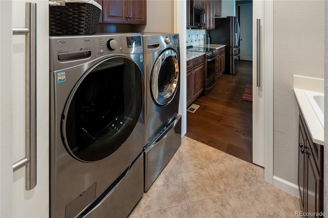 clothes washing area with cabinet space, light tile patterned floors, visible vents, and washer and clothes dryer