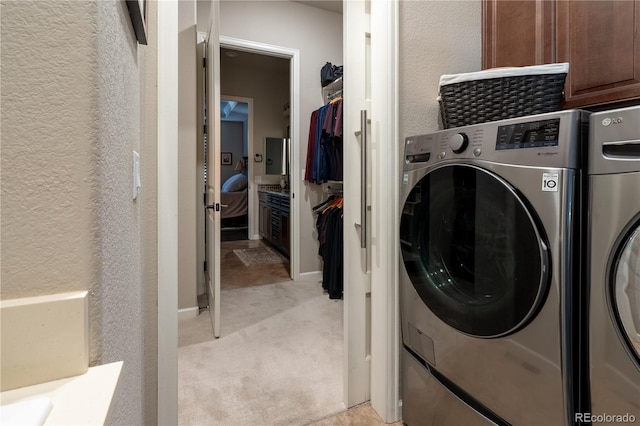 laundry area with washer and dryer, cabinet space, a textured wall, and light carpet