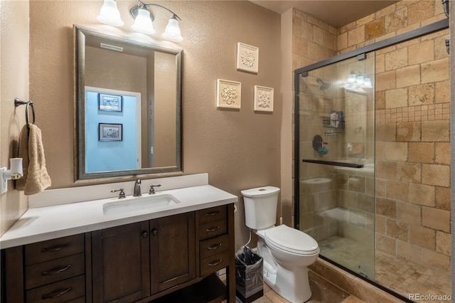 bathroom with a stall shower, vanity, and toilet