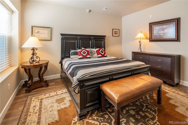 bedroom with wood finished floors, visible vents, and baseboards