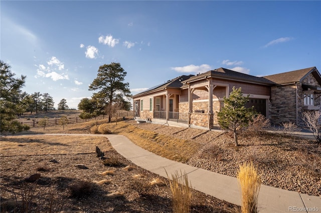 view of side of home featuring roof mounted solar panels, fence, and an attached garage