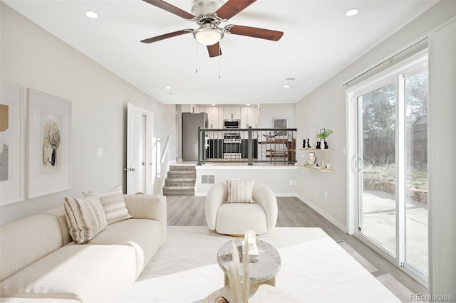 living area featuring recessed lighting, stairway, light wood-style floors, and ceiling fan