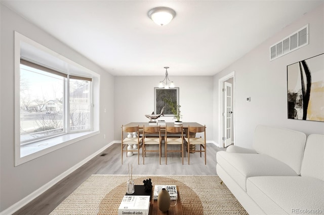 dining room with a notable chandelier, wood finished floors, visible vents, and baseboards