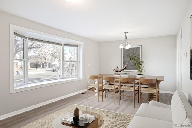 dining area featuring visible vents, baseboards, a notable chandelier, and wood finished floors