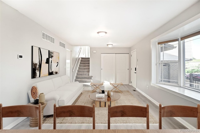 living area with visible vents, baseboards, wood finished floors, and stairs