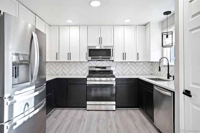 kitchen featuring dark cabinetry, white cabinets, appliances with stainless steel finishes, and a sink