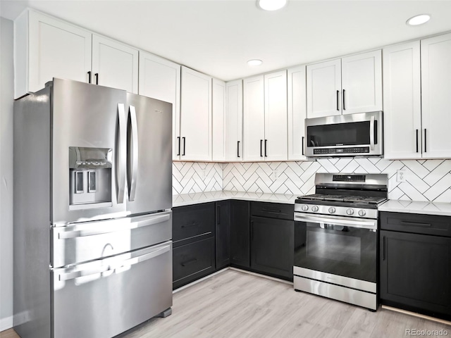 kitchen with backsplash, light countertops, light wood-style floors, white cabinets, and stainless steel appliances