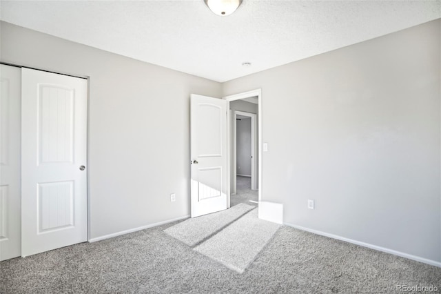 unfurnished bedroom featuring carpet flooring, a textured ceiling, and baseboards