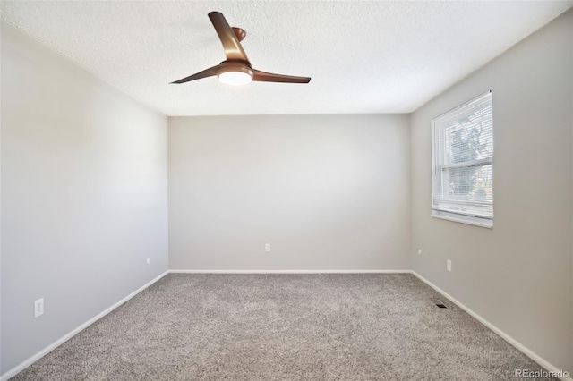 carpeted empty room with baseboards, visible vents, a textured ceiling, and a ceiling fan