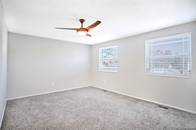 unfurnished room featuring visible vents, baseboards, carpet, a textured ceiling, and a ceiling fan