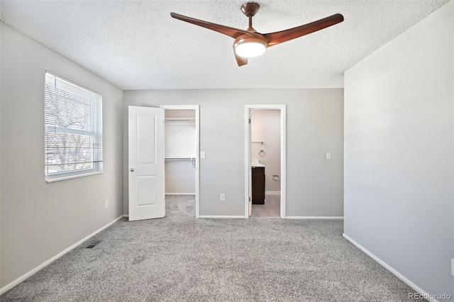 unfurnished bedroom featuring a walk in closet, visible vents, carpet, and baseboards