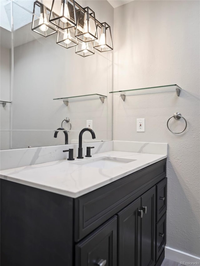 bathroom with baseboards, vanity, and a textured wall