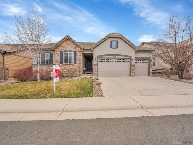 view of front of house featuring stone siding, a front lawn, concrete driveway, and an attached garage