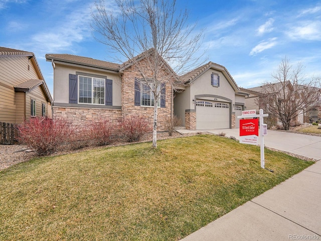 view of front of home with concrete driveway, a front yard, stucco siding, stone siding, and an attached garage