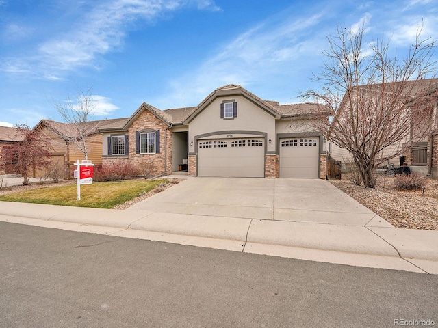 view of front of property with stucco siding, a front lawn, driveway, stone siding, and a garage