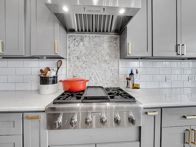kitchen with backsplash, gray cabinetry, extractor fan, stainless steel gas cooktop, and light stone counters