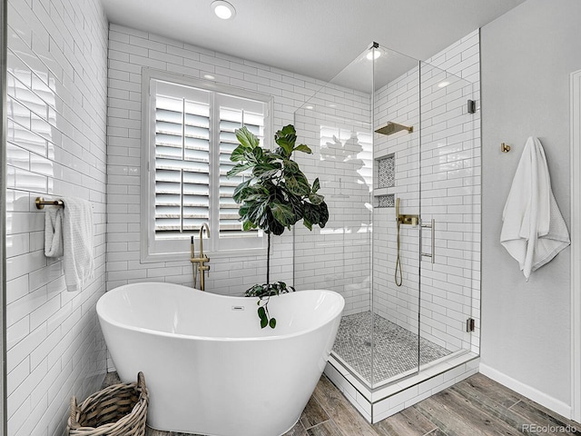 bathroom featuring a shower stall, a freestanding tub, tile walls, and wood finished floors
