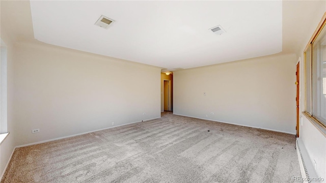 unfurnished room with light colored carpet and a baseboard heating unit