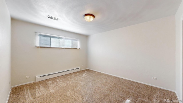 carpeted spare room featuring a baseboard heating unit