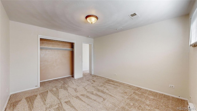 unfurnished bedroom featuring light carpet and a closet