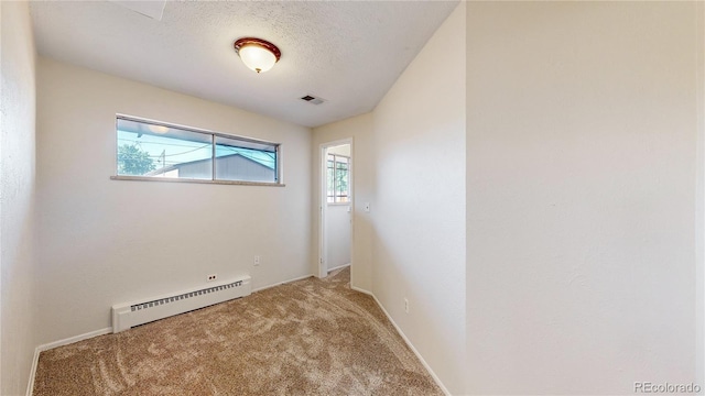 spare room with carpet flooring, a textured ceiling, and a baseboard heating unit