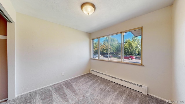 spare room with carpet and a baseboard heating unit