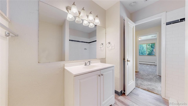 bathroom with hardwood / wood-style floors, vanity, walk in shower, and a baseboard radiator