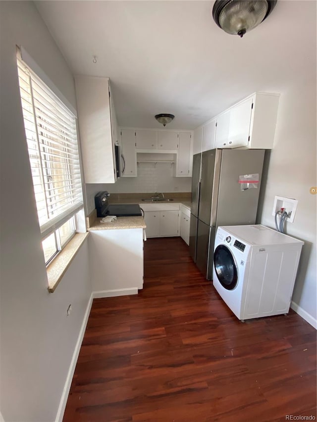 kitchen with sink, dark hardwood / wood-style flooring, washer / dryer, white cabinets, and appliances with stainless steel finishes