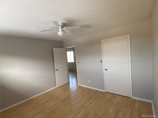 unfurnished bedroom with ceiling fan, a baseboard heating unit, a closet, and light hardwood / wood-style flooring