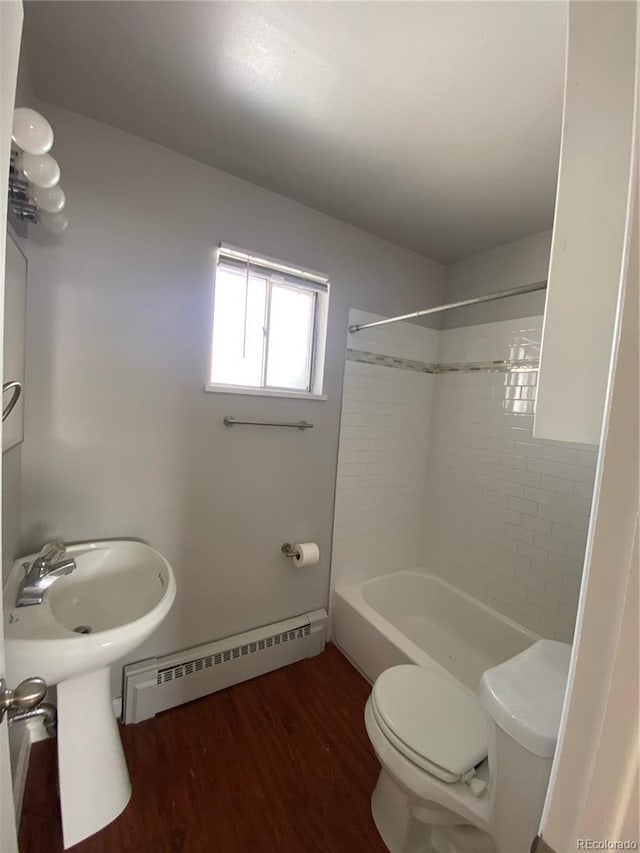 bathroom featuring tiled shower / bath combo, toilet, wood-type flooring, and baseboard heating