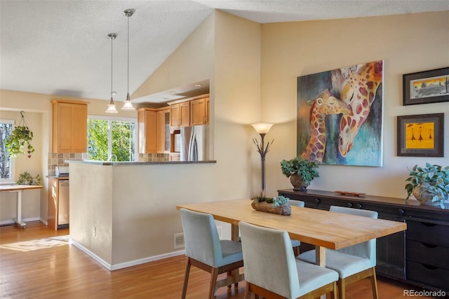11446 W 105th Dr, Broomfield, CO 80021 - dining area with baseboards, light wood finished floors, and lofted ceiling