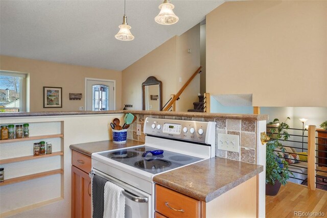 11446 W 105th Dr, Broomfield, CO 80021 - kitchen with brown cabinetry, dark countertops, white range with electric stovetop, light wood finished floors, and decorative light fixtures