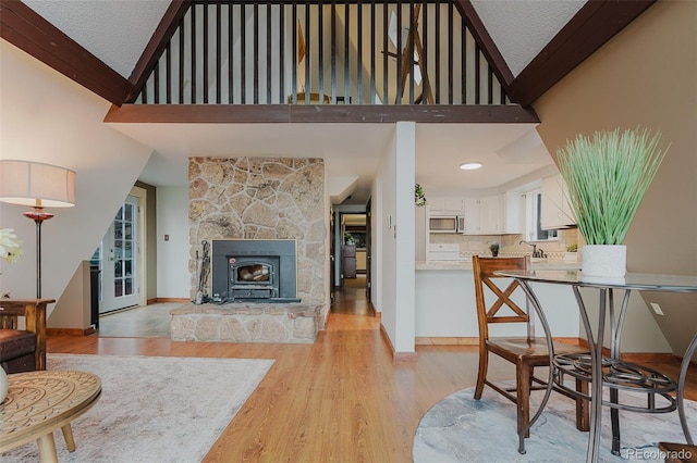 8691 S Warhawk Rd, Conifer, CO 80433 - living area with high vaulted ceiling, light wood-style floors, a textured ceiling, and baseboards