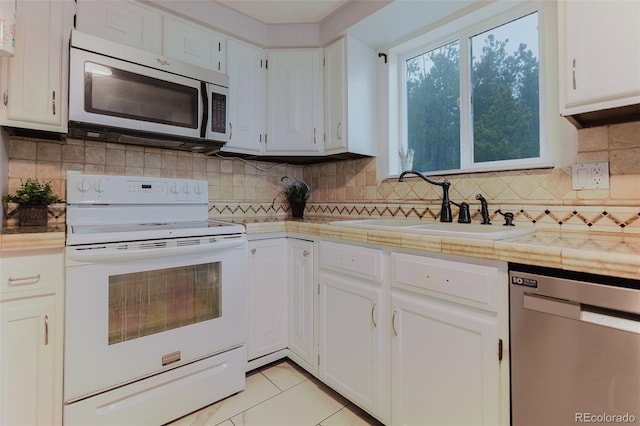 8691 S Warhawk Rd, Conifer, CO 80433 - kitchen with appliances with stainless steel finishes, a sink, white cabinetry, backsplash, and light tile patterned floors