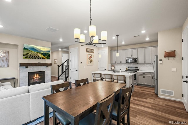 dining space with dark hardwood / wood-style flooring, a fireplace, and a chandelier