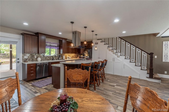 kitchen featuring stainless steel appliances, a kitchen island, light countertops, tasteful backsplash, and island exhaust hood