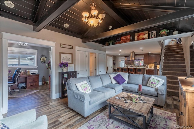 living room featuring a chandelier, vaulted ceiling with beams, light wood-style flooring, and stairs