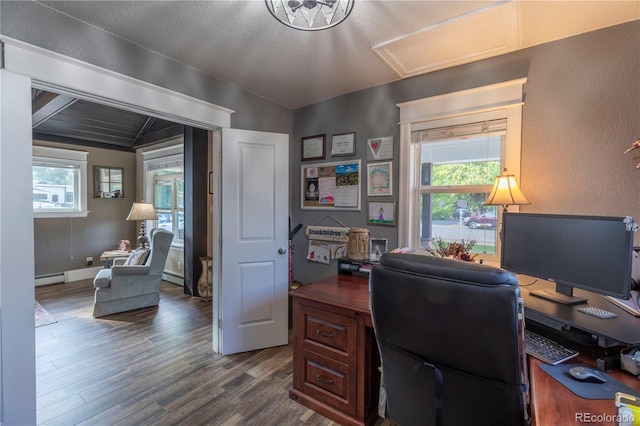 office space featuring a baseboard radiator, plenty of natural light, vaulted ceiling, and dark wood finished floors