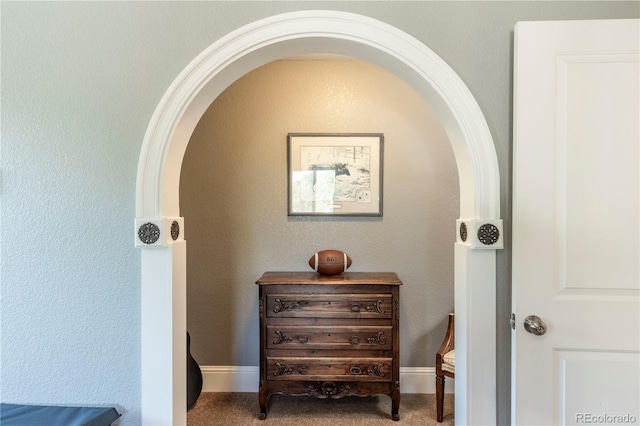 interior space featuring arched walkways and carpet flooring