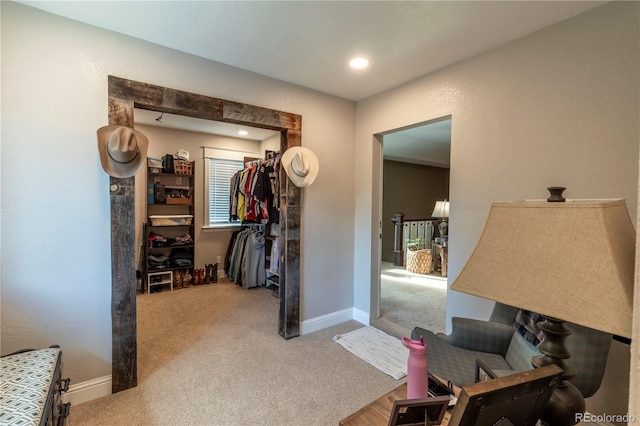 corridor featuring carpet, baseboards, and an upstairs landing