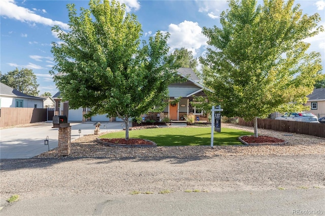 obstructed view of property featuring fence, concrete driveway, and a front yard