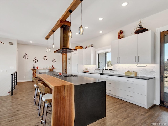 kitchen with island exhaust hood, a kitchen bar, modern cabinets, light wood-type flooring, and backsplash