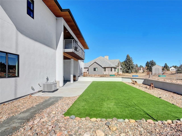 view of yard with a balcony, a patio area, and central AC