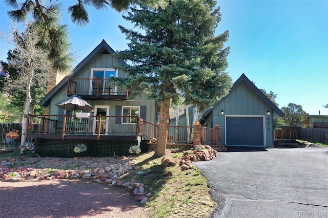 rustic home featuring a balcony, board and batten siding, a garage, and fence