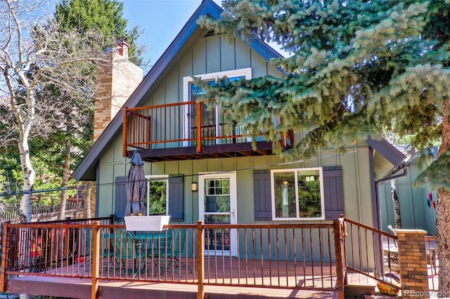 back of property featuring a chimney, board and batten siding, and a wooden deck