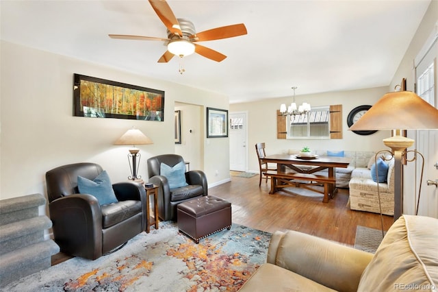 living area with ceiling fan with notable chandelier, a healthy amount of sunlight, and wood finished floors