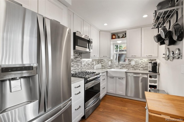 kitchen featuring a sink, stainless steel appliances, light countertops, and white cabinets