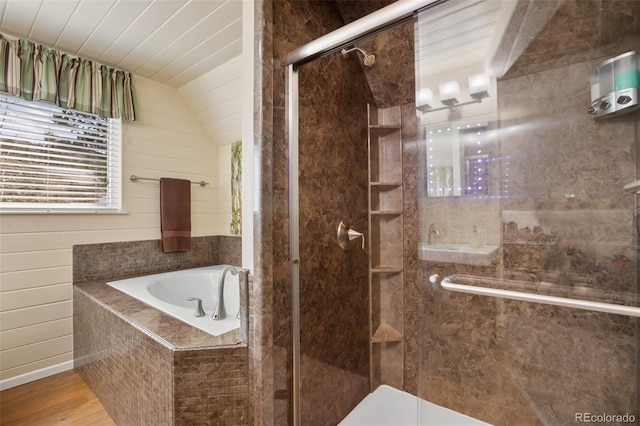 full bath featuring vaulted ceiling, a stall shower, a bath, and wood finished floors